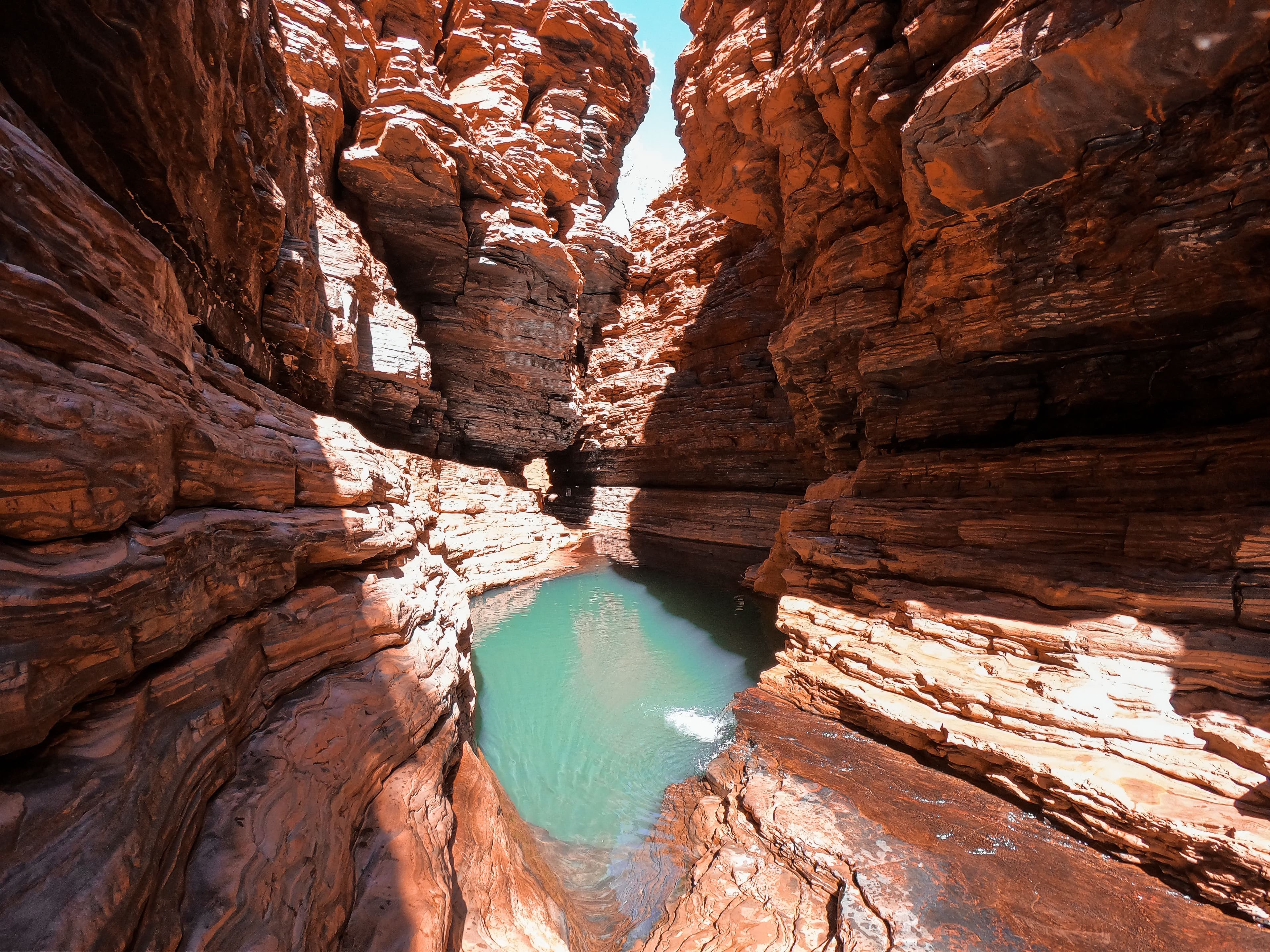 the deep, narrow chasm of Handcock Gorge features layered rock formations and a clear pool of water at the bottom